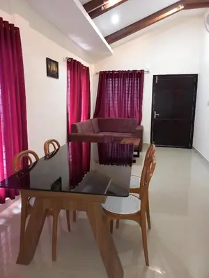 a dining room with a table and chairs and red curtains at Whiteflower Mountain Resort in Perintalmanna