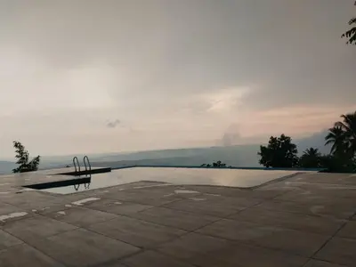 a swimming pool with a bench in front of it at Whiteflower Mountain Resort in Perintalmanna