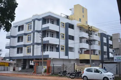 a white building with motorcycles parked in front of it at Golden Bells in Vānivilāsa Puram
