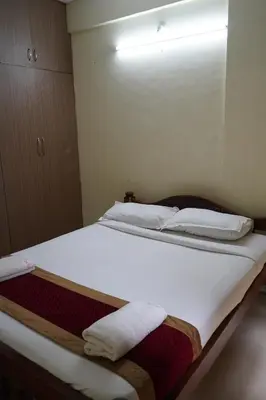 a bedroom with a large bed with white sheets and pillows at Golden Bells in Vānivilāsa Puram