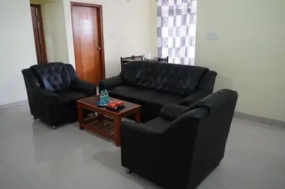 a living room with two black couches and a coffee table at Golden Bells in Vānivilāsa Puram