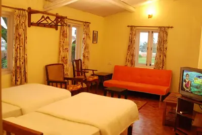 a living room with two beds and a television at Bella Vista Homestay in Coonoor