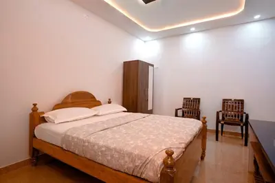 a bedroom with a large bed and two chairs at Nagadeep Residency in Mysore