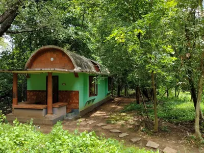 a small green building in the middle of trees at Sradha Farm Stay - Kollengode in Kollengode