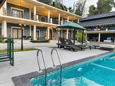a house with a swimming pool in front of a house at Villa Forever Coorg in Madikeri