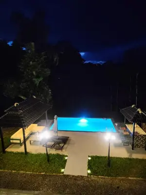 a swimming pool at night with two umbrellas at Villa Forever Coorg in Madikeri