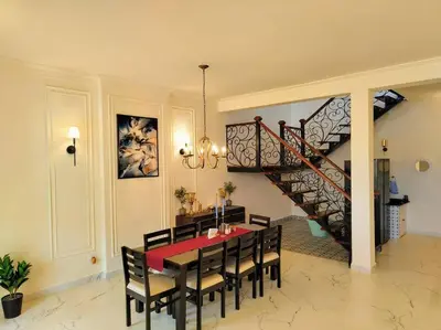 a dining room with a table and chairs and a staircase at Villa Forever Coorg in Madikeri