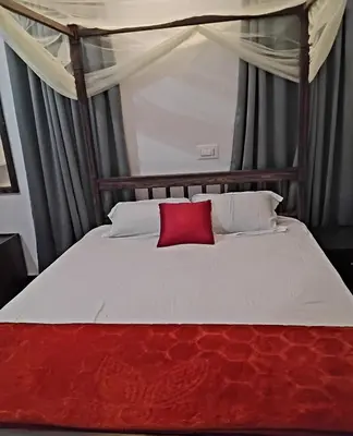 a bed with a red pillow on top of it at Mitra retreats in Mānantoddy