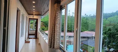 a hallway with large windows and a view of a mountain at Hornbill Castle in Vālpārai