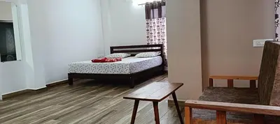 a bedroom with a bed and a table and a bench at Hornbill Castle in Vālpārai