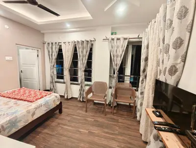 a bedroom with a bed and two chairs and a tv at Hornbill Castle in Vālpārai