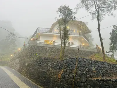 a house on top of a stone wall in the fog at Brooke hills falls view in Vallikavungal