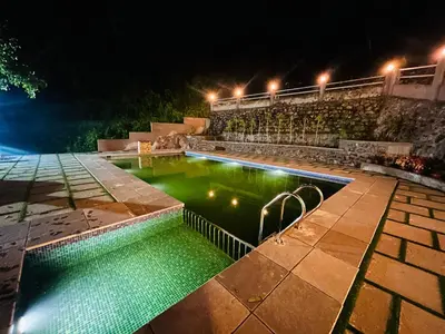 a swimming pool with green water at night at Brooke hills 2 BHK villa falls view in Vallikavungal