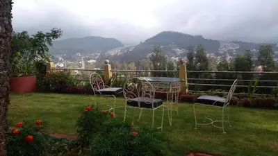 a table and chairs in a yard with a view at Wyoming Heritage in Ooty