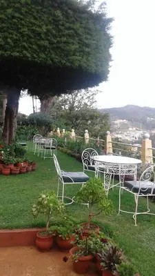 a group of chairs and a table in a garden at Wyoming Heritage in Ooty
