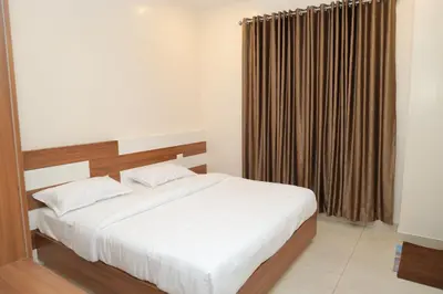 a bedroom with a bed and a window with curtains at Hotel BR Grand in Coimbatore