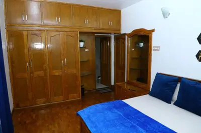 a bedroom with wooden cabinets and a bed with blue sheets at Pine Hood Villa in Ooty