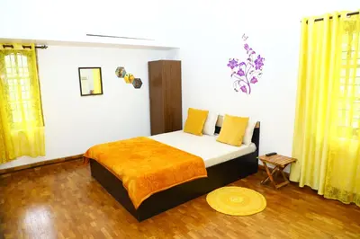 a bedroom with a bed with a yellow blanket on it at Pine Hood Villa in Ooty