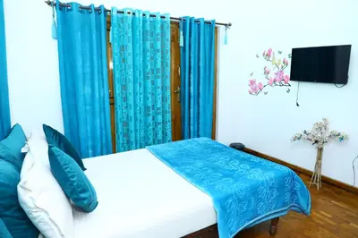 a bedroom with a bed with a blue curtain at Pine Hood Villa in Ooty