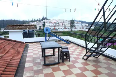 a balcony with a table and stairs on a building at Pine Hood Villa in Ooty