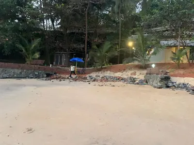 a person with an umbrella walking on the beach at Rocks beach house in Kannur