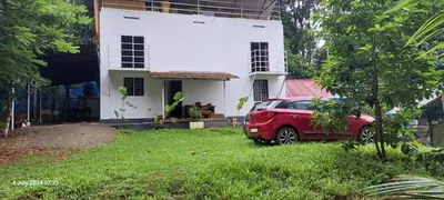 a red car parked in front of a white house at Randukai Farm House in Athirappally