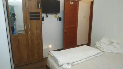 a room with a bed and a cabinet and a television at Randukai Farm House in Athirappally