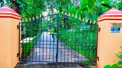 a gate in a garden with a path through it at Rustic Retreat in Perumbavoor