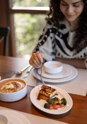 a woman sitting at a table with a plate of food at LohonoStays Villa Amani 8B in Coonoor