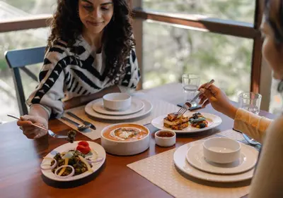 a woman sitting at a table with plates of food at LohonoStays Villa Amani 8B in Coonoor