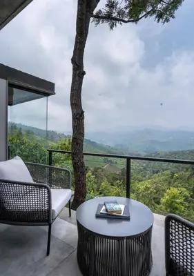 a balcony with a table and chairs and a tree at LohonoStays Amani Villa 9A in Coonoor