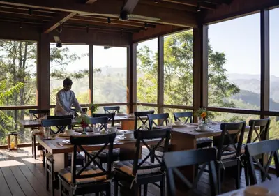a man standing in a dining room with tables and chairs at LohonoStays Amani Villa 9B in Coonoor