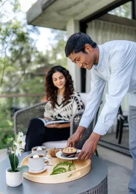a man preparing a plate of food on a table at LohonoStays Amani Villa 9B in Coonoor