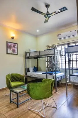 a room with bunk beds and chairs and a ceiling fan at Beedu - Backpackers Hostel in Mysore