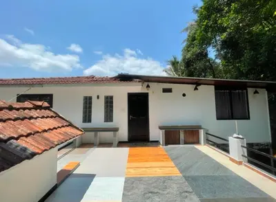 a white house with a patio and a table at Tjmaryland villa in Pinangode