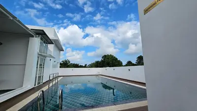 a swimming pool on the side of a building at Prosland Hotel in Tirūr