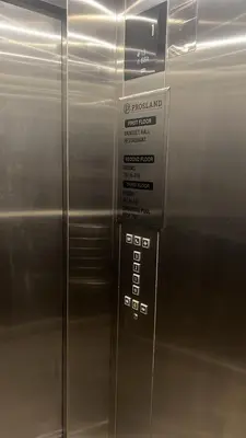 a metal elevator with a sign on the side of it at Prosland Hotel in Tirūr