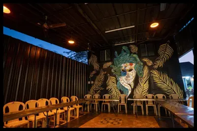 a stage with chairs and a large painting of a lion at Serene Meadows Resort in Kāramadai
