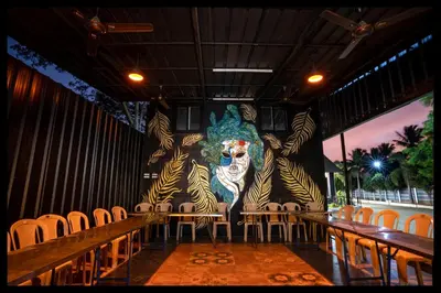 a room with chairs and a wall with a painting of a face at Serene Meadows Resort in Kāramadai