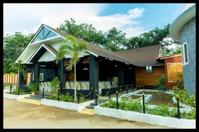a house with a palm tree in front of it at Serene Meadows Resort in Kāramadai