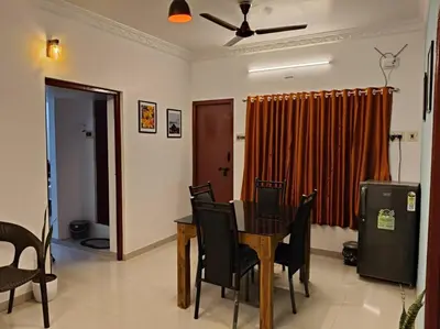 a dining room with a table and black chairs at Padmam Service Apartments - 2BHK in Singānallūr