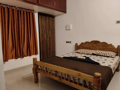 a bedroom with a wooden bed and a window at Padmam Service Apartments - 2BHK in Singānallūr