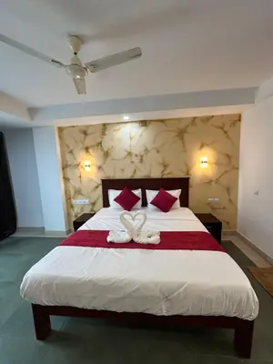 a bedroom with a large white bed with red pillows at CRYSTAL Inn in Kalpetta
