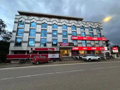 a large building with cars parked in front of it at CRYSTAL Inn in Kalpetta