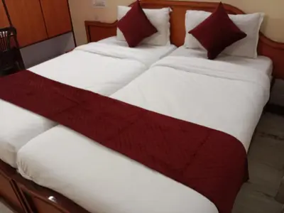 two twin beds with red and white sheets at Mysuru-hotel in Mysore