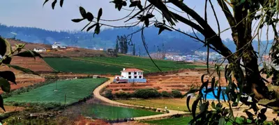 a view of a hill with a house and a river at AJ Groups B&B Residency in Ooty