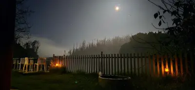 a fence with chairs in a yard at night at RR Forest View in Ooty