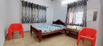 a bedroom with two red chairs and a bed at Nature stay Mysore in Mandya
