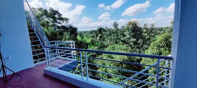 a balcony with a staircase and a view of trees at Nature stay Mysore in Mandya
