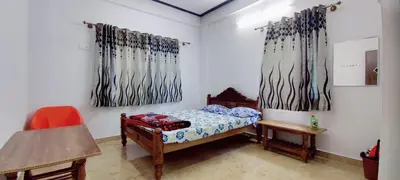 a bedroom with a bed and two paintings on the wall at Nature stay Mysore in Mandya